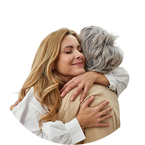 A blonde woman with closed eyes smiles warmly while embracing a person with grey hair.