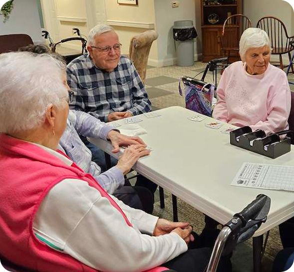 Smiling seniors enjoy a friendly card game around a table.