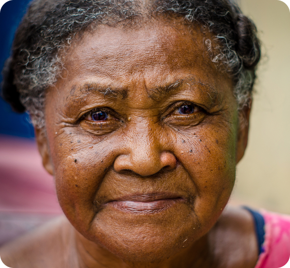 An older Black woman with graying hair and a gentle expression looks directly forward.