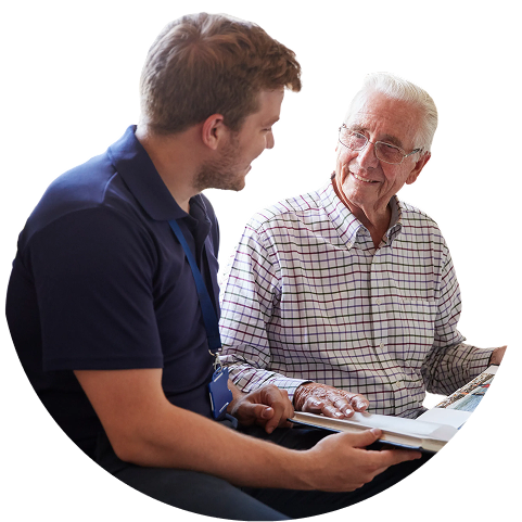 A smiling senior man and a younger man look at a photo album together. TITLE: