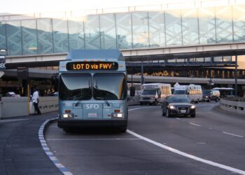 A bus driving down the street with cars on it.