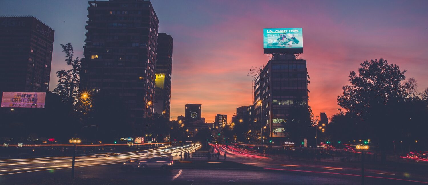 A city street with cars driving on it at night.