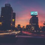 A city street with cars driving on it at night.