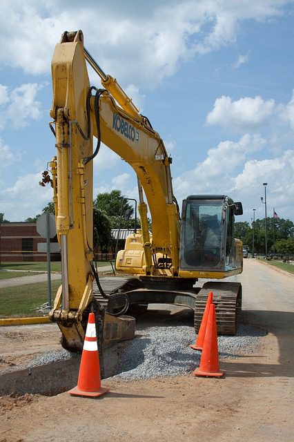 A yellow and black excavator sitting on top of asphalt.