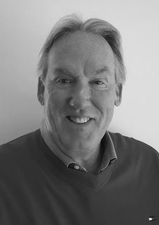 A black and white photo of a man smiling.