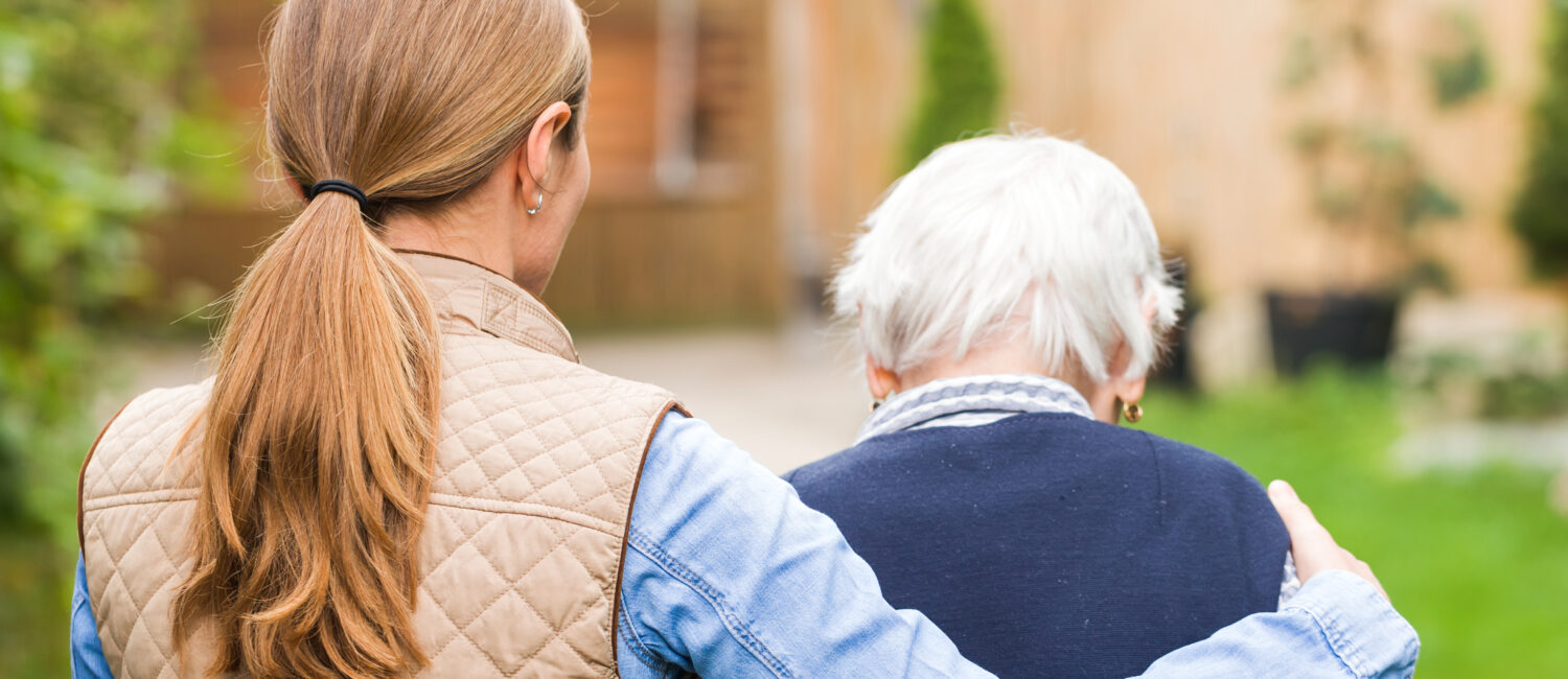 A woman and an older man are hugging outside.