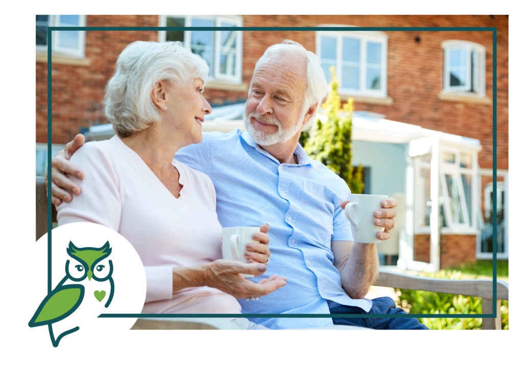 An older couple sitting on a bench with coffee.