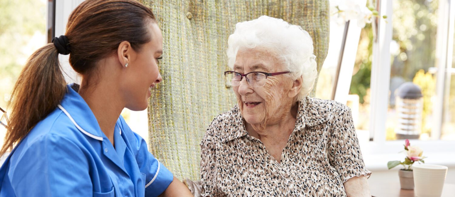 A nurse talking to an older woman in a room.