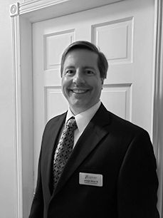 A man in suit and tie standing next to a door.