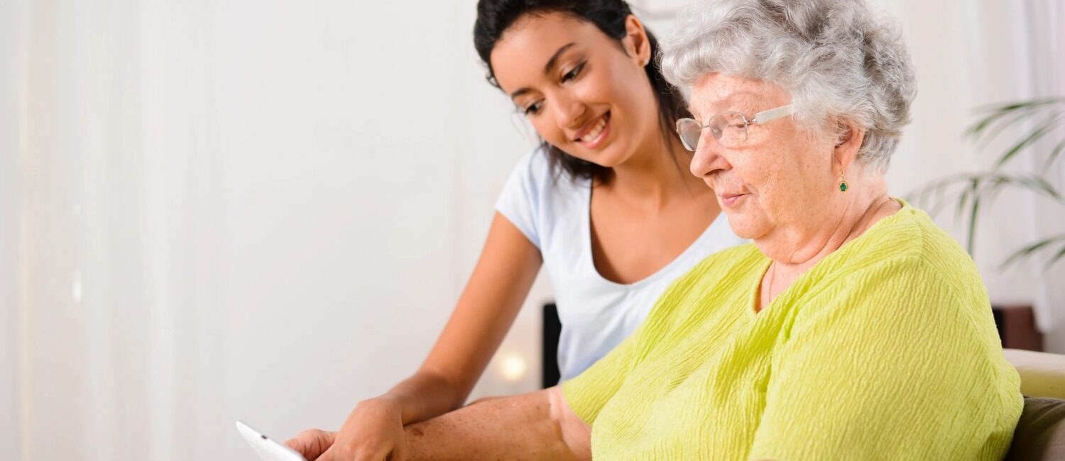 A woman and an older person looking at something on a tablet.