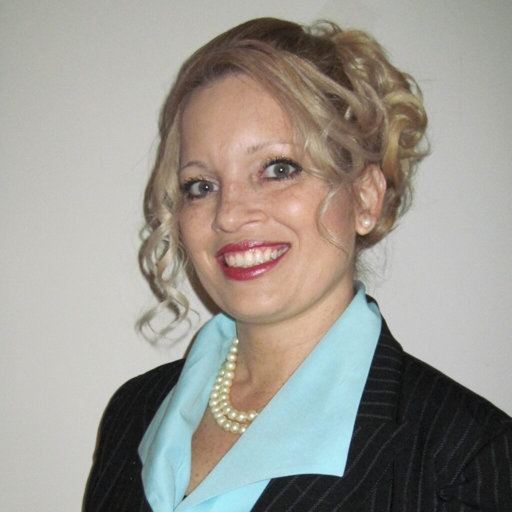 A woman in a black jacket and pearls