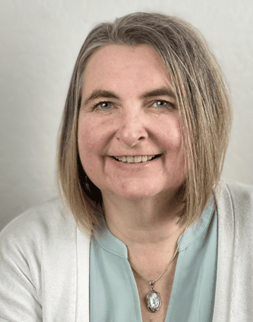 A woman with short hair wearing a white cardigan.